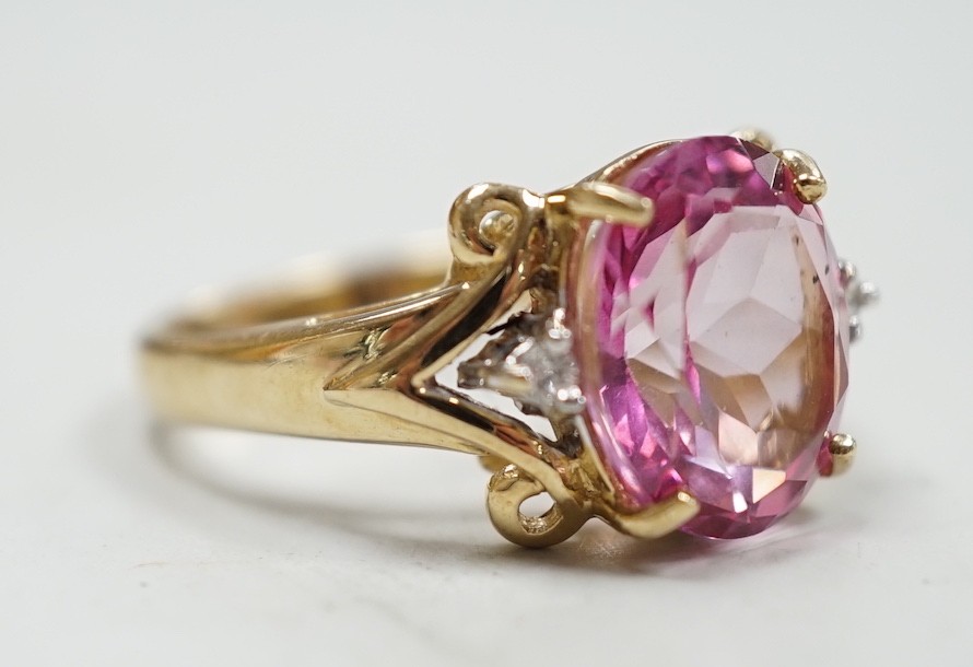 A modern 9ct gold and single stone oval cut flamingo topaz dress ring with two stone diamond set shoulders, size N, gross weight 5.3 grams, with Gems TV certificate.